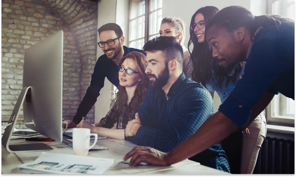 Image: team collaborating on a computer.