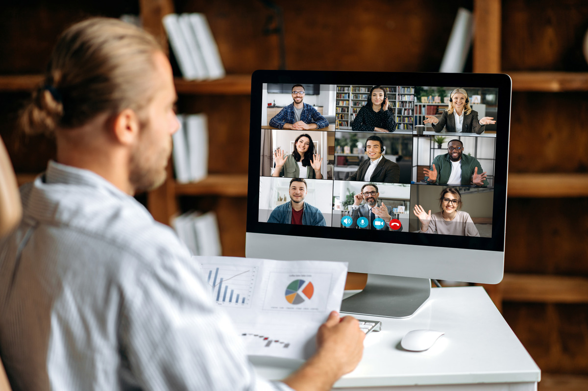 A manager leading a video meeting with a distributed team while reviewing data charts