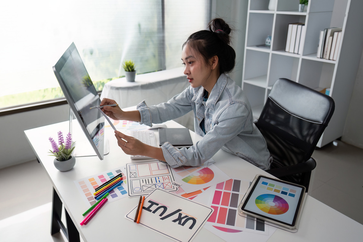 Early-career designer reviewing UX/UI colour palettes at a desk