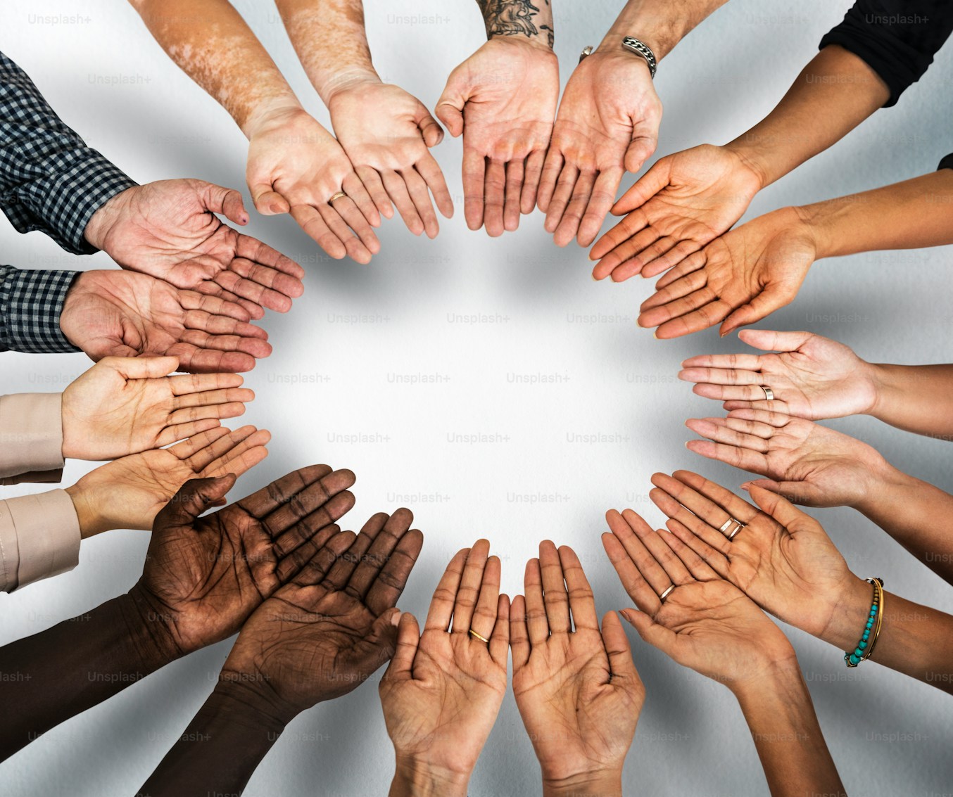 Diverse group of people reaching their open hands together in a circle