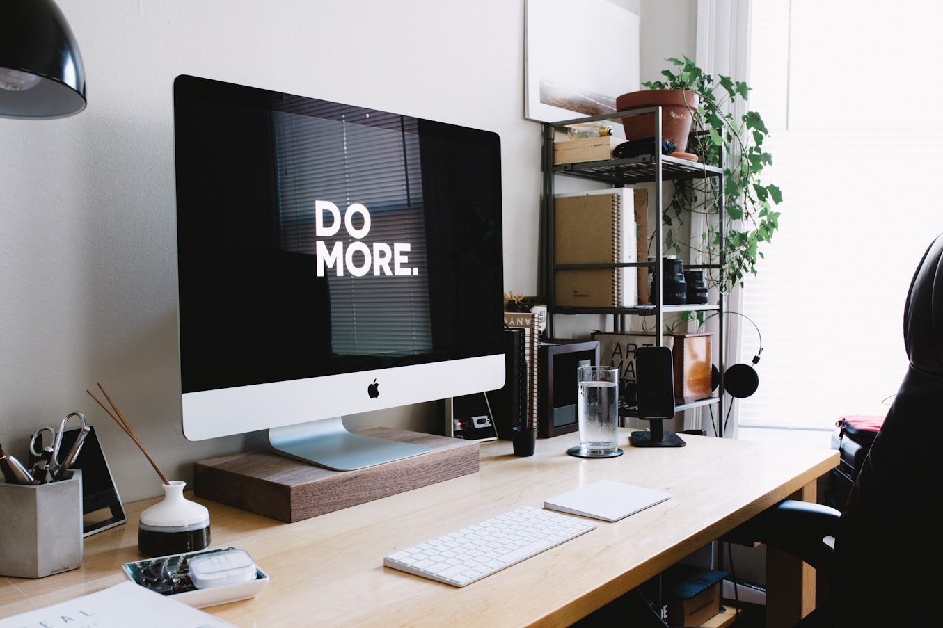 A modern workspace with an iMac displaying the message Do More